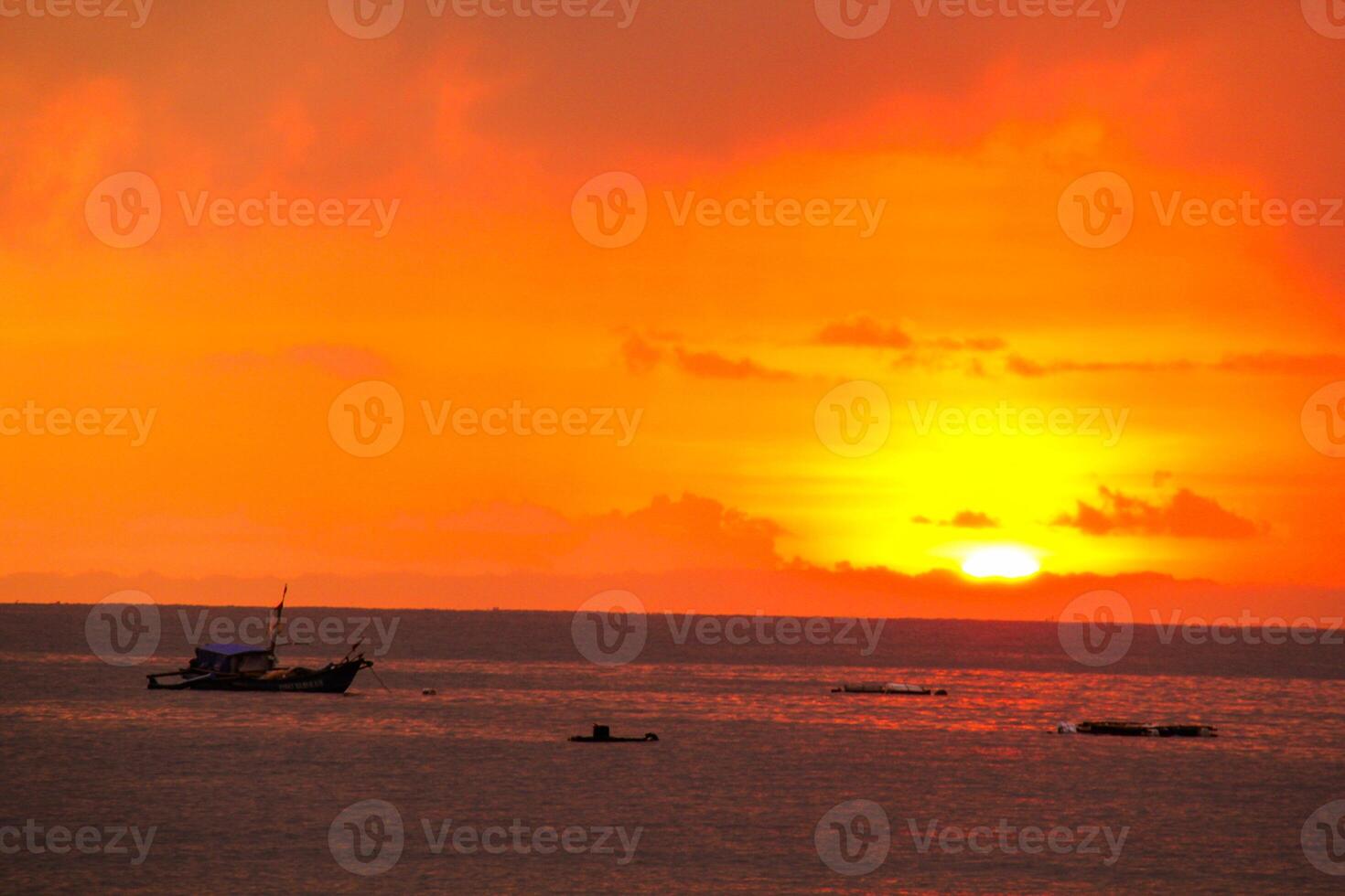 A boat is out in the ocean at sunset photo