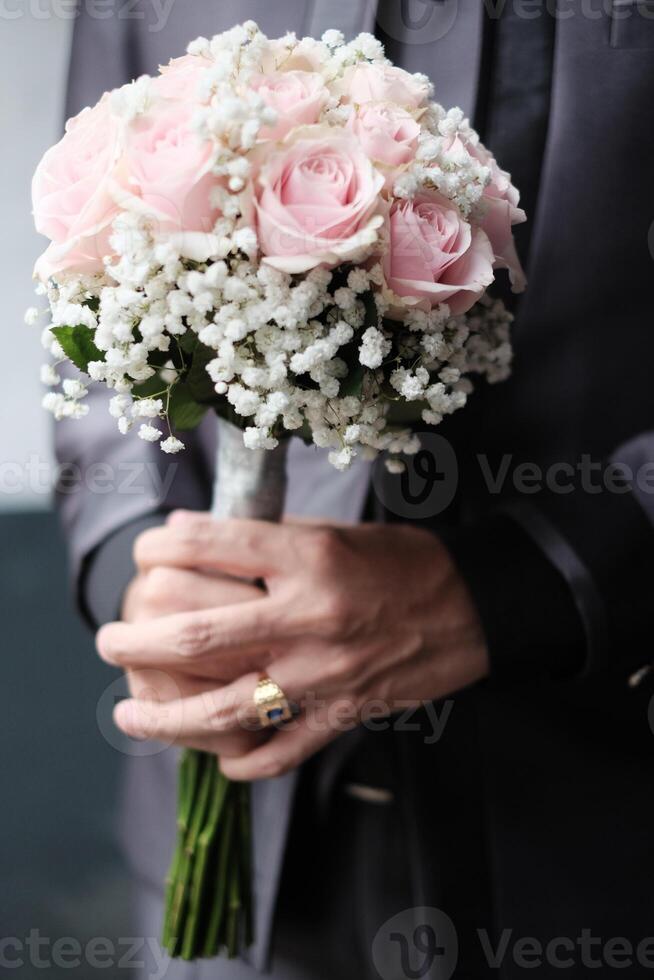 Groom holding a beautiful pink rose bouquet photo