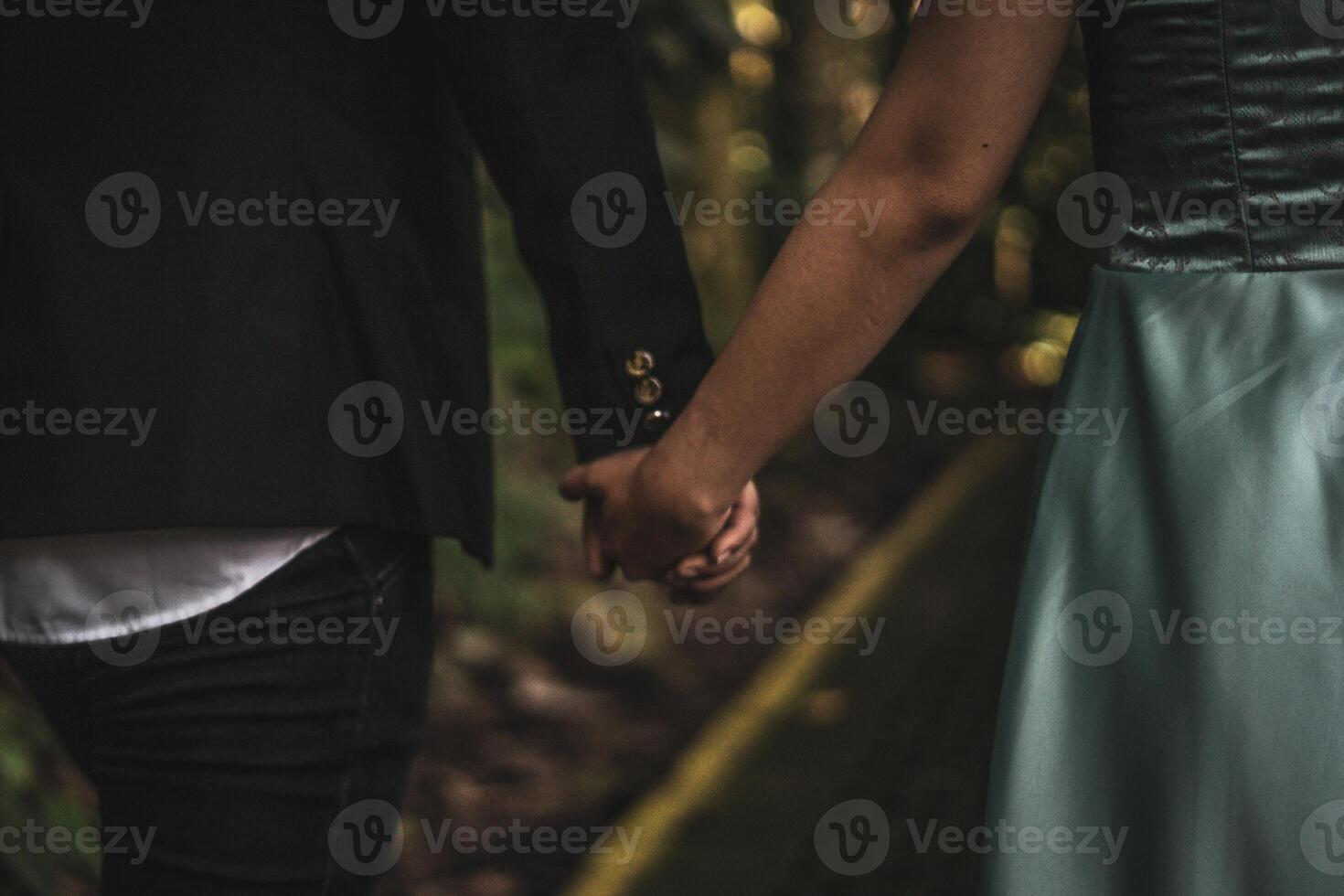 Couple holding hands intimately in a forest, expressing love and connection photo