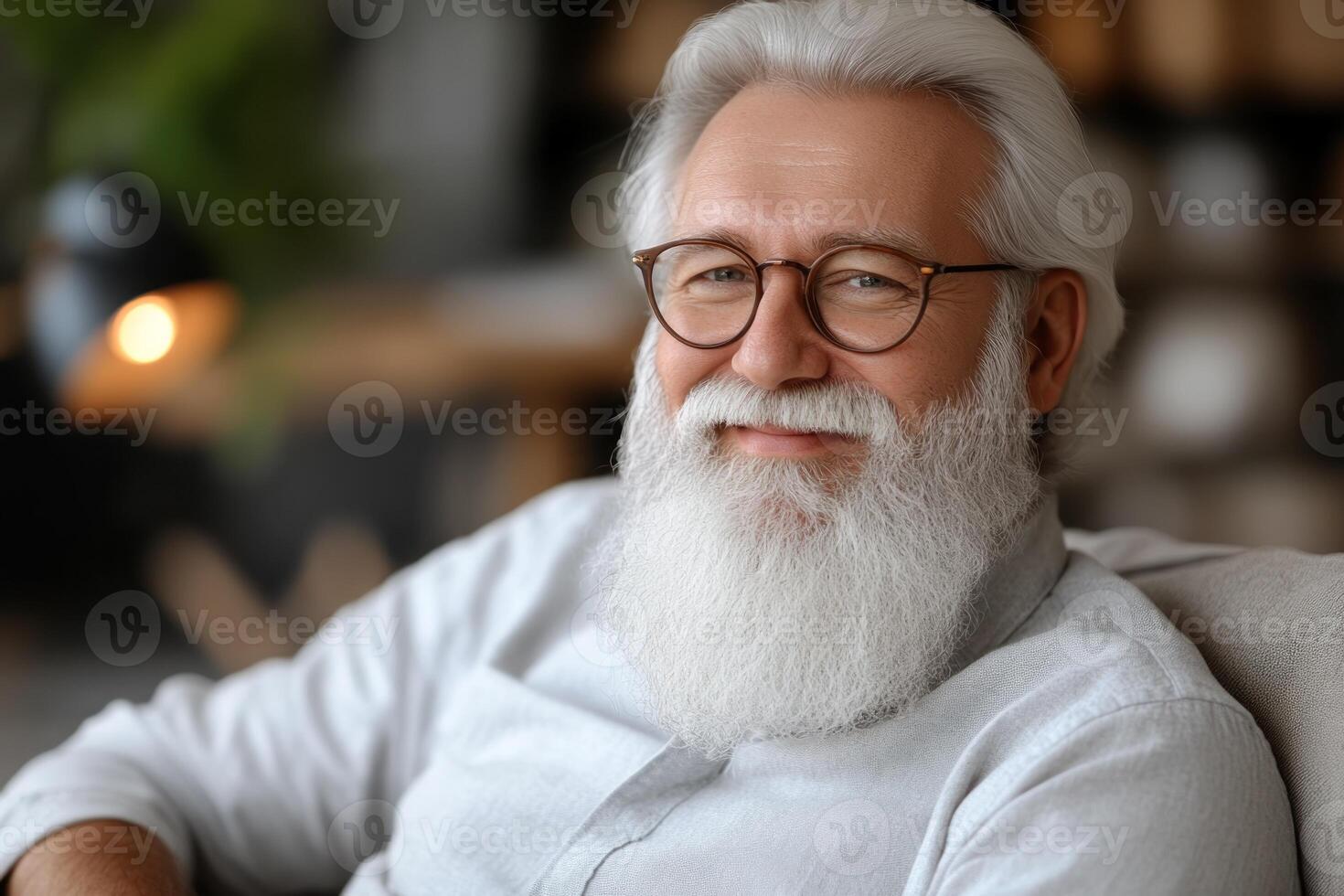 Smiling senior man with a long white beard and glasses relaxing in a cozy indoor setting photo