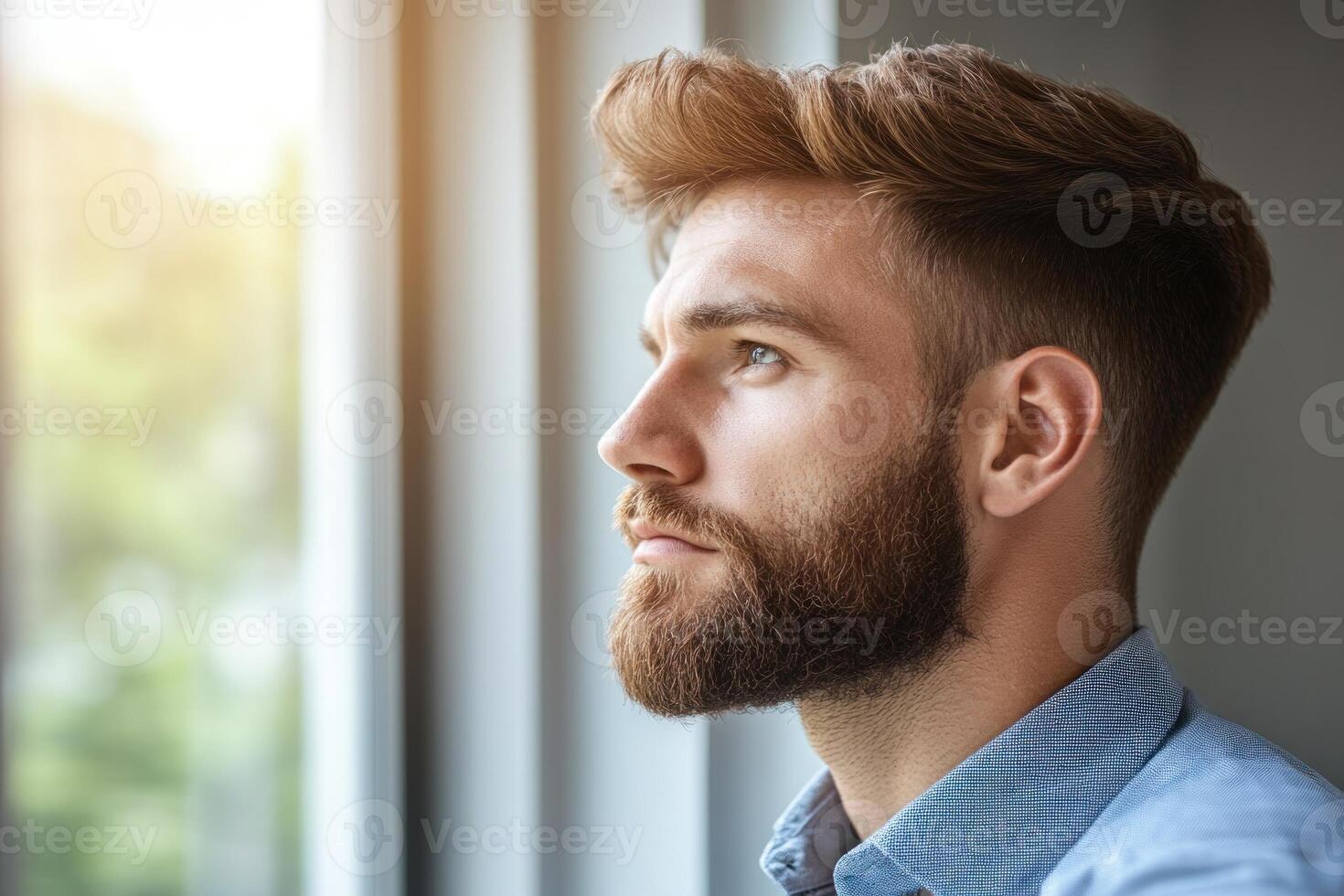Thoughtful young man gazes out the window, contemplating life on a sunny day photo