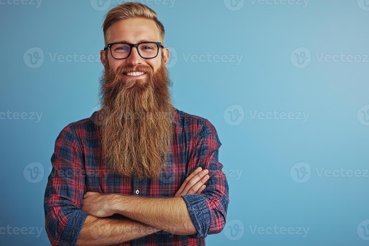 Stylish man with a long beard and glasses poses confidently against a blue background photo