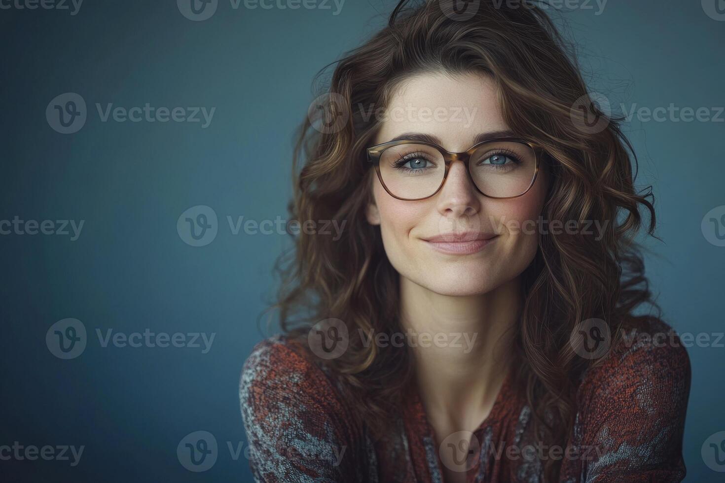 Woman with curly hair wearing glasses smiles in a relaxed setting with neutral background photo