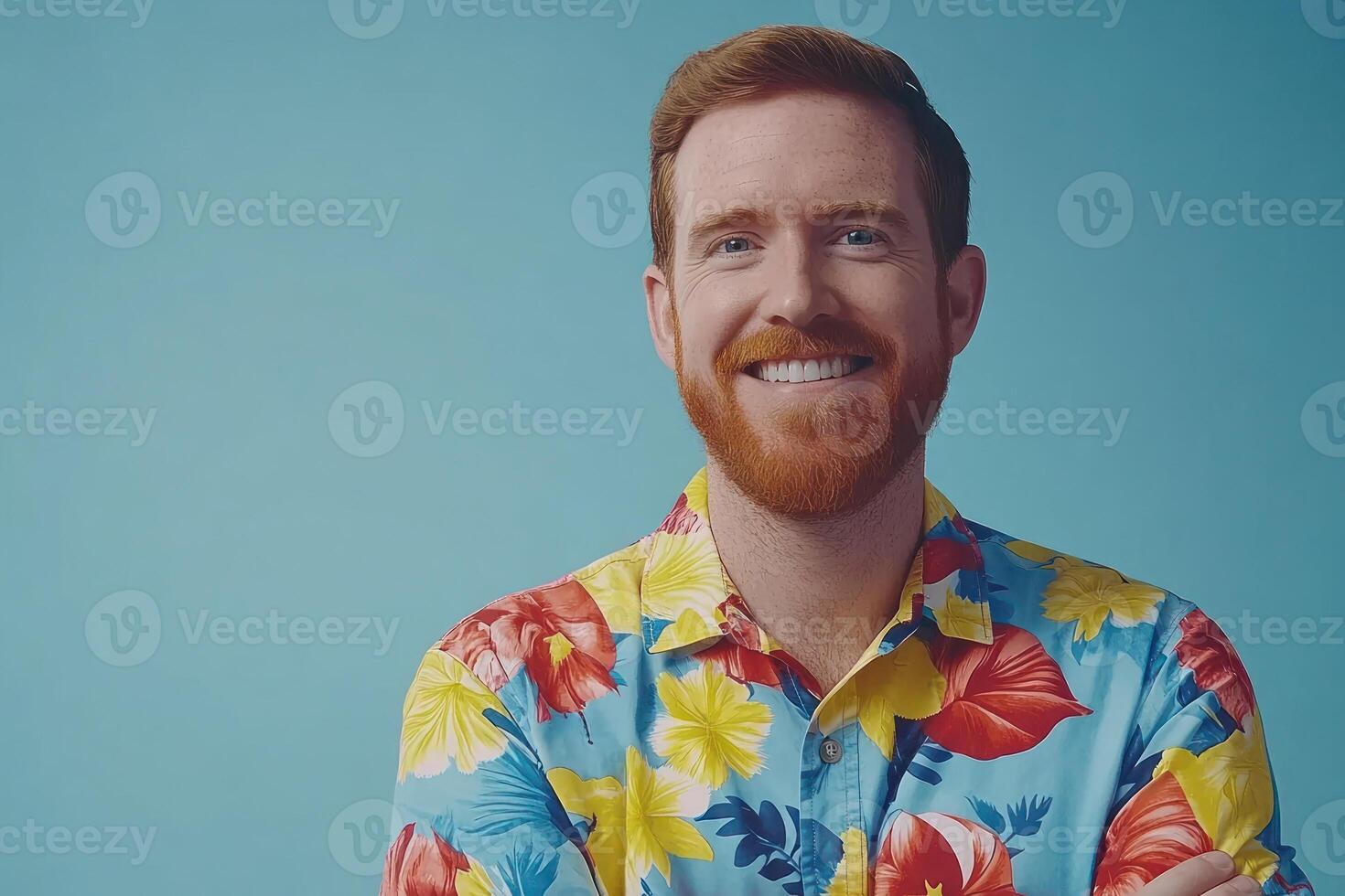 Man wearing a colorful floral shirt smiles against a bright blue background in casual portrait photo
