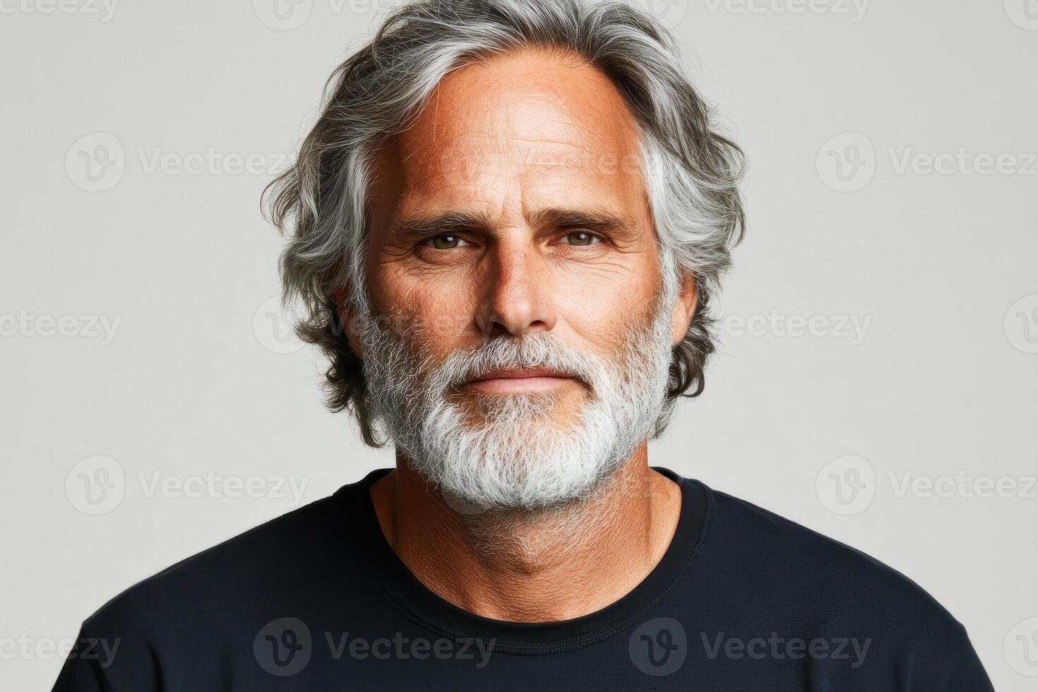 Mature man with silver hair and beard posing confidently against a neutral background photo
