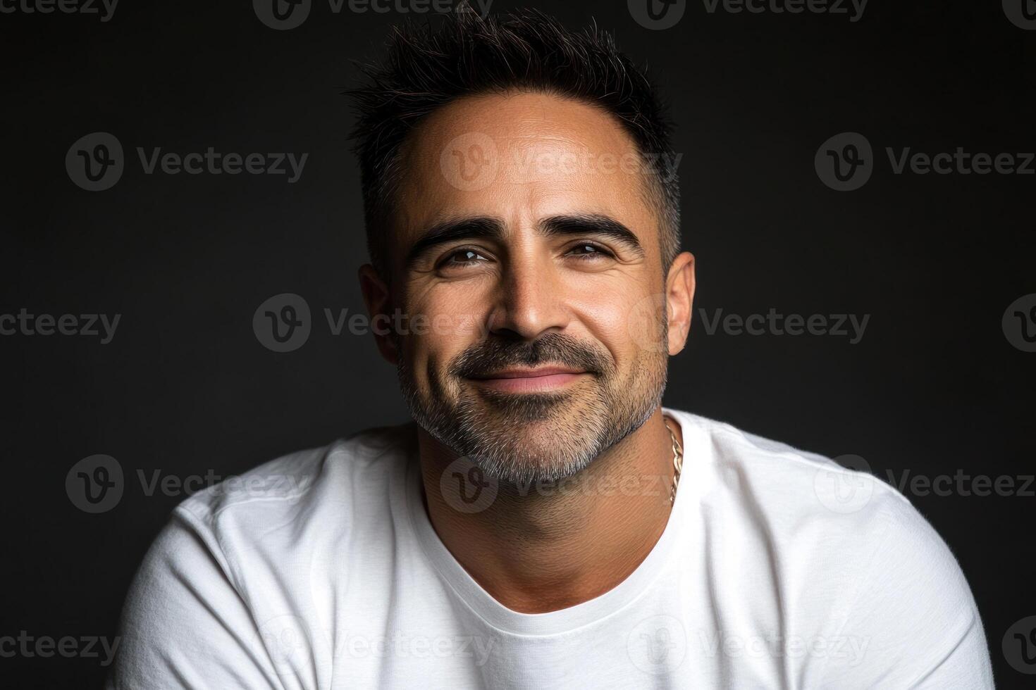 Portrait of a smiling man with short dark hair wearing a white shirt against a dark background photo