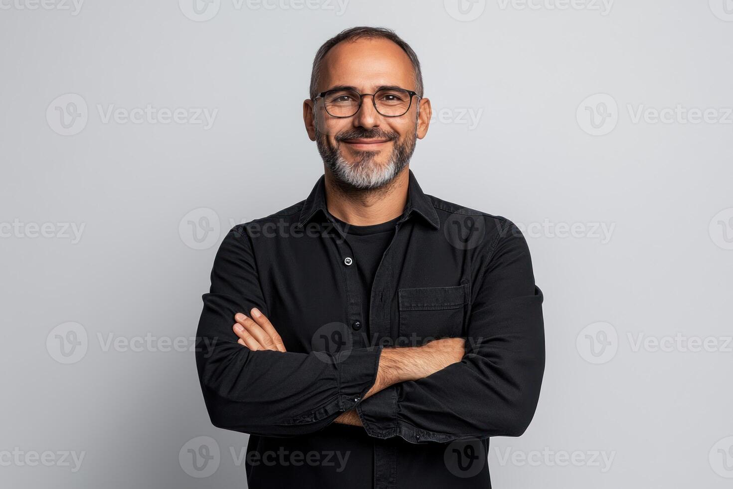 Confident man smiling with crossed arms against light gray background in casual attire photo