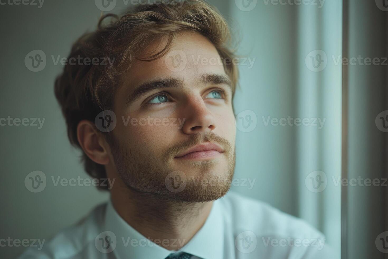 Thoughtful young man gazing out window during quiet moment of reflection and contemplation photo