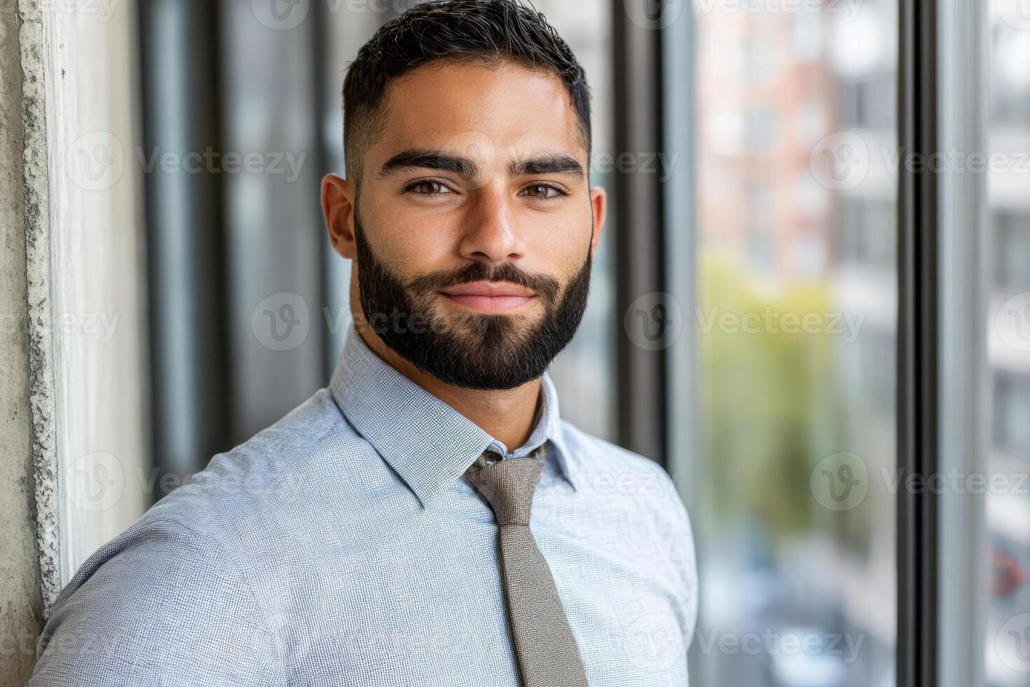 Professional man poses confidently in modern office with large windows and urban view photo
