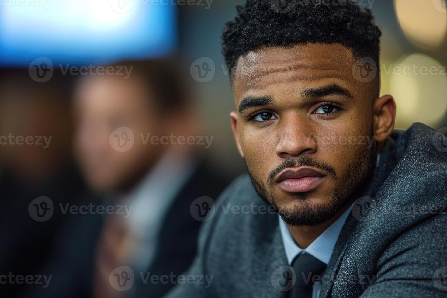 Young man in a suit engages in conversation during a formal event at a dimly lit venue photo
