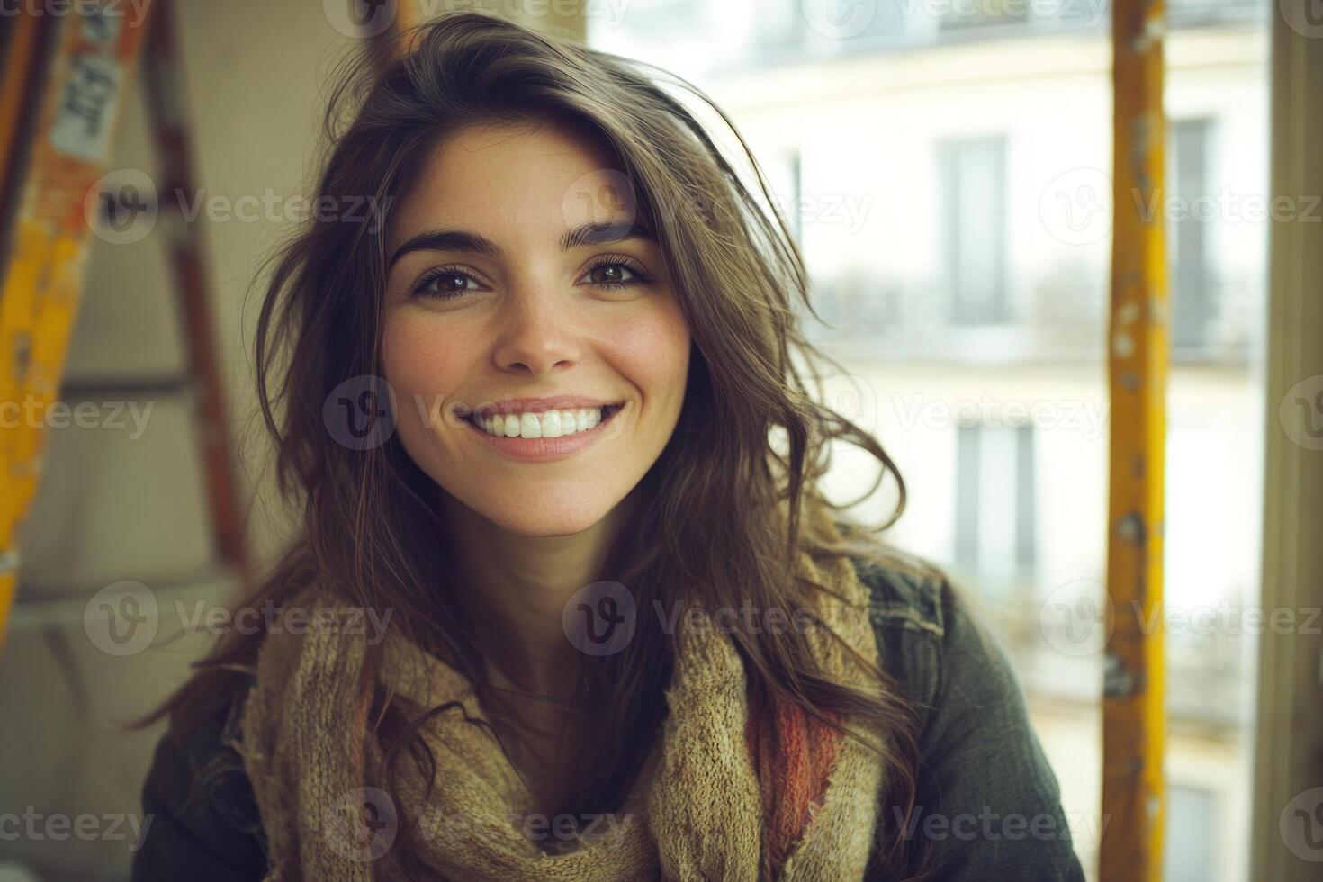 Young woman smiling brightly indoors near a window with a ladder in the background photo
