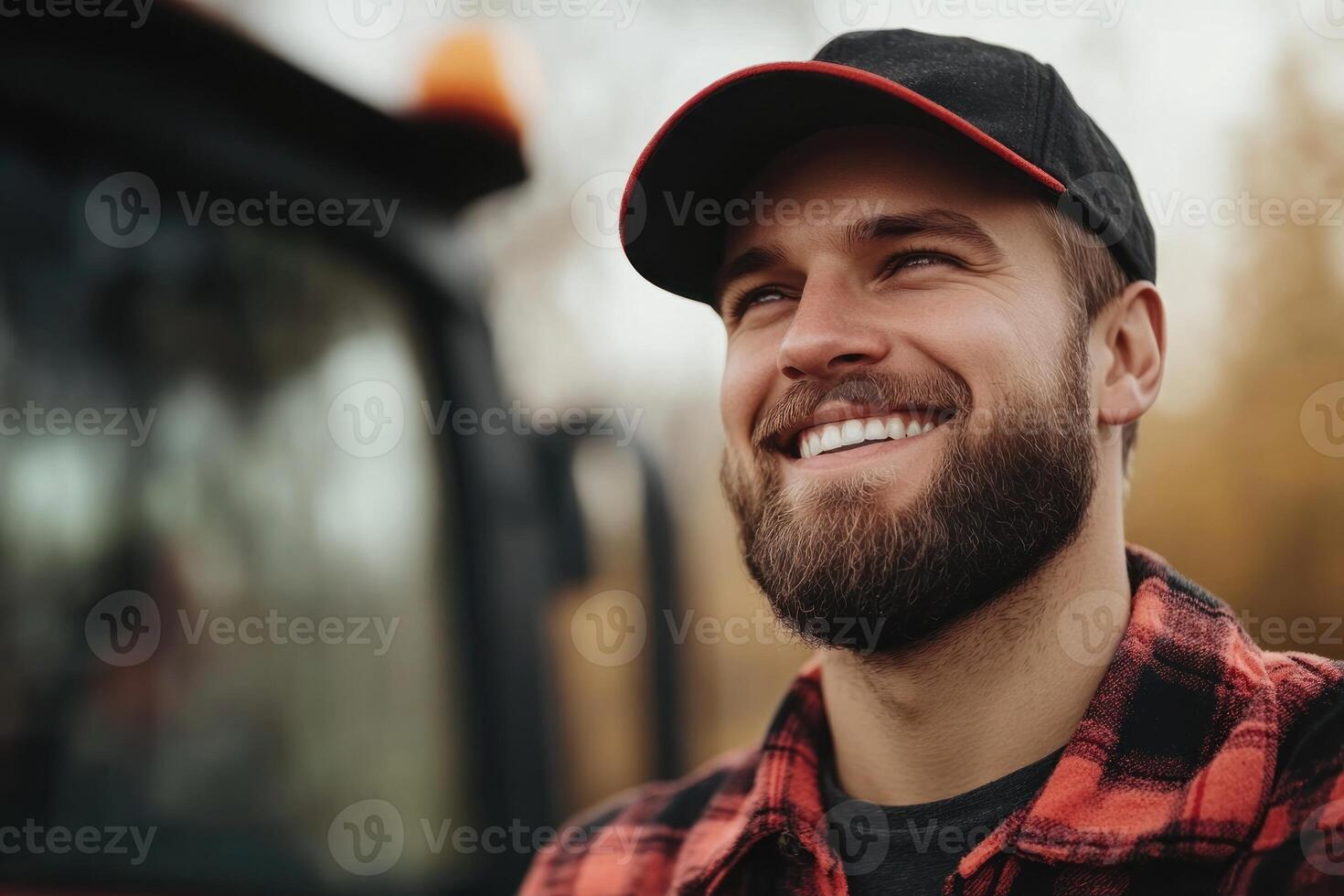 Smiling farmer with beard stands near tractor during autumn season in rural landscape photo