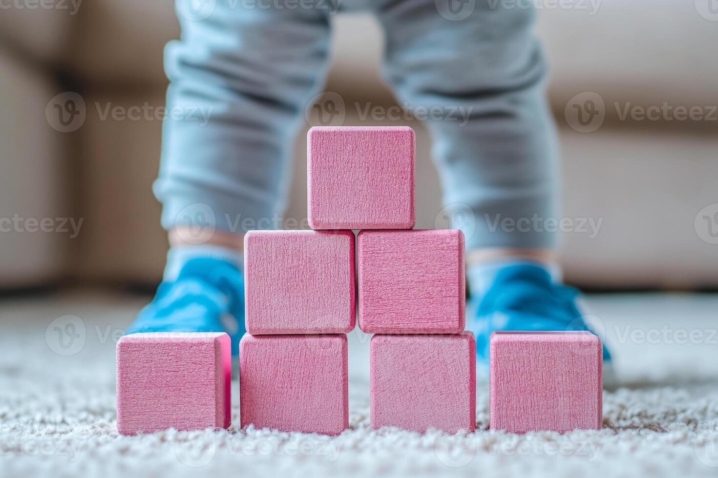 child plays with pink wooden building blocks, stacking them in the form of a tower photo