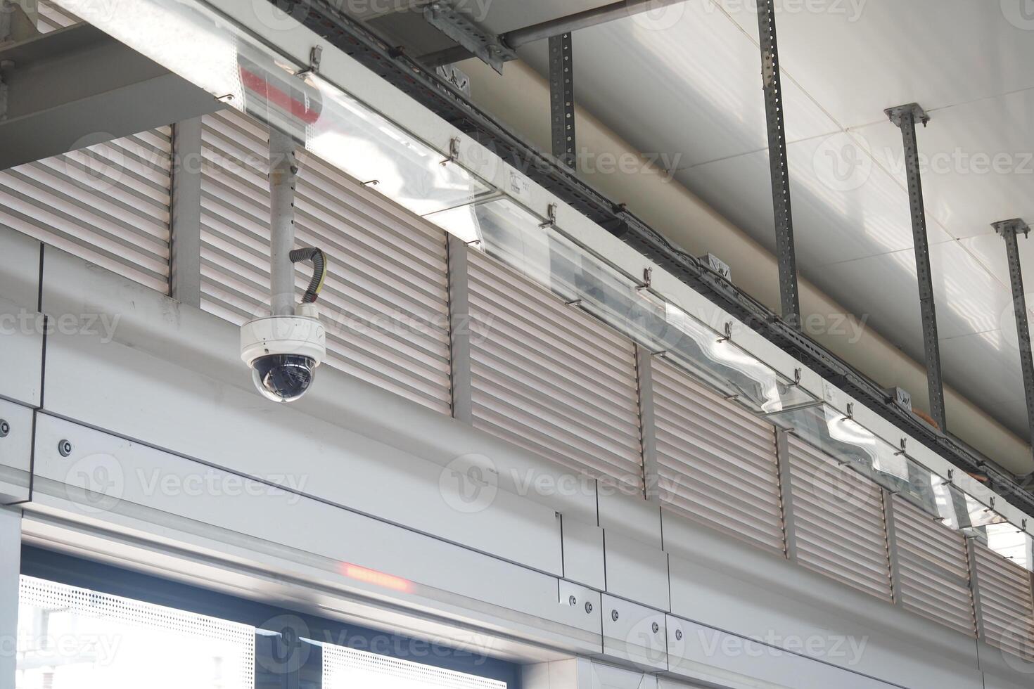 Security camera mounted on industrial ceiling in a modern building photo