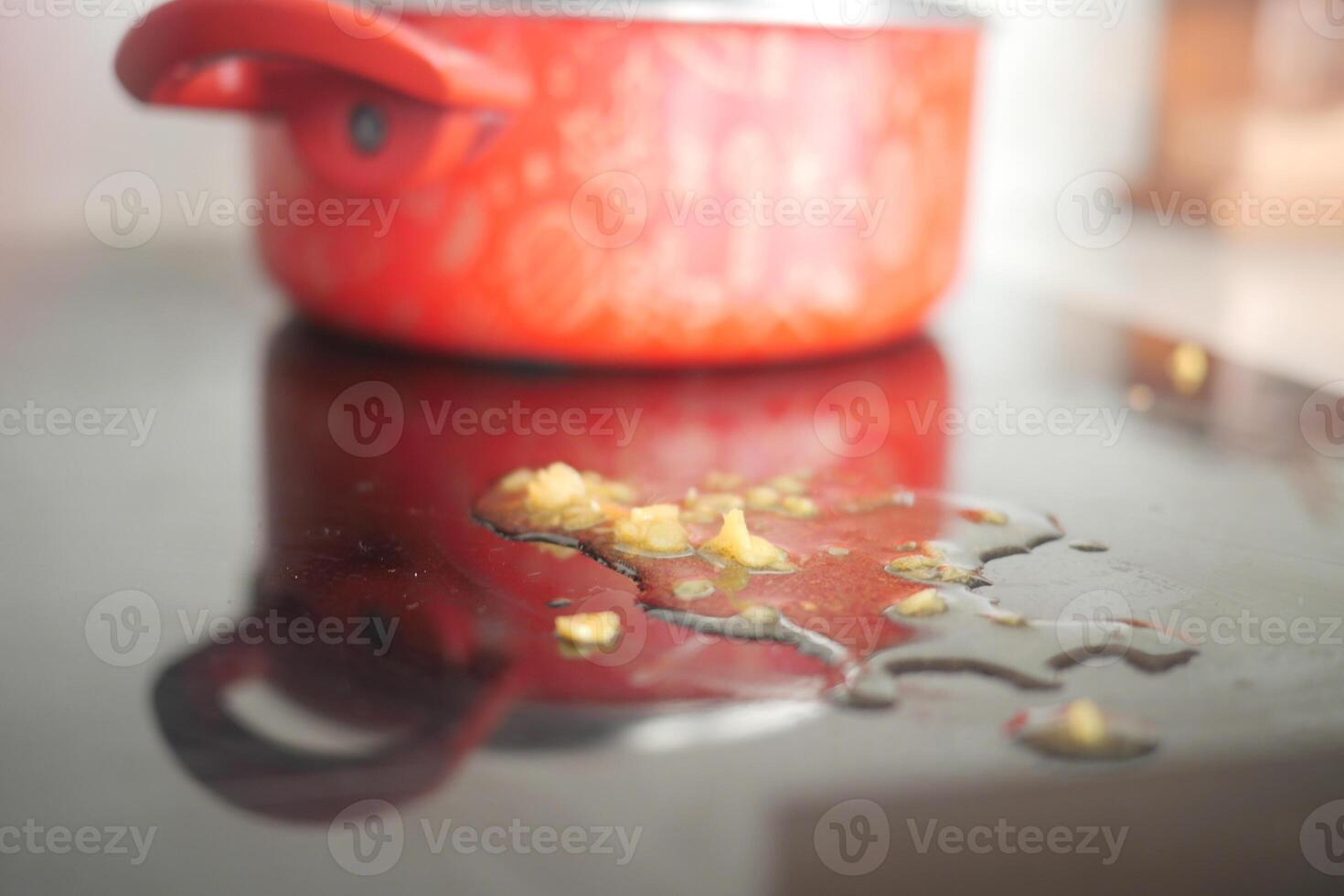 Cooking process with oil spill on countertop near red pot photo