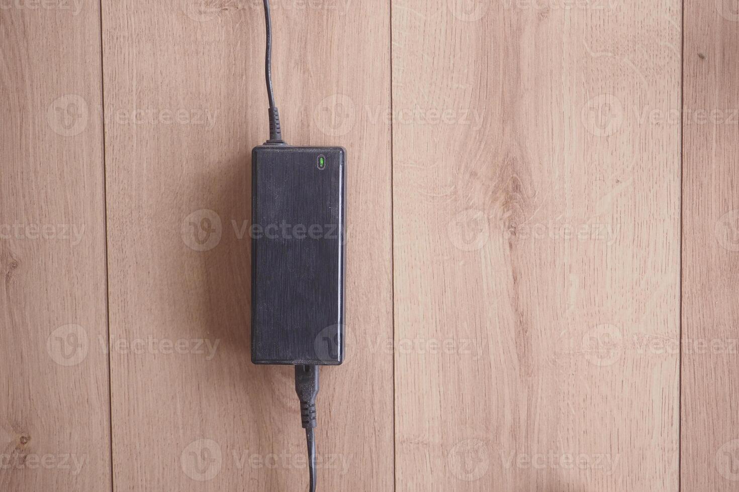 Power adapter resting on wooden surface with cable attached photo