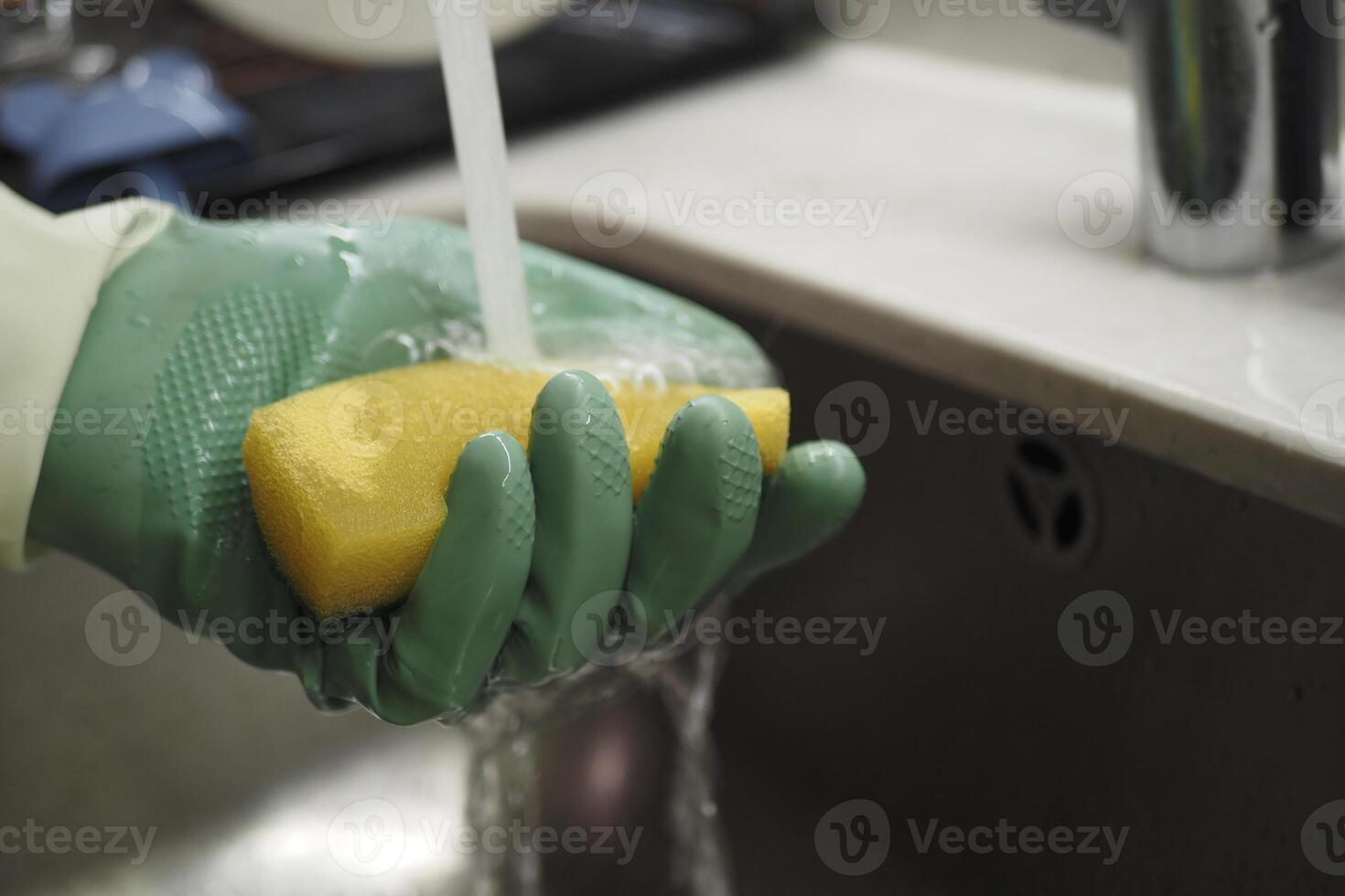 Washing a sponge under running water at the kitchen sink photo