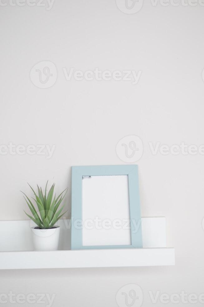 Simple decor with a plant and a blank picture frame on a shelf photo