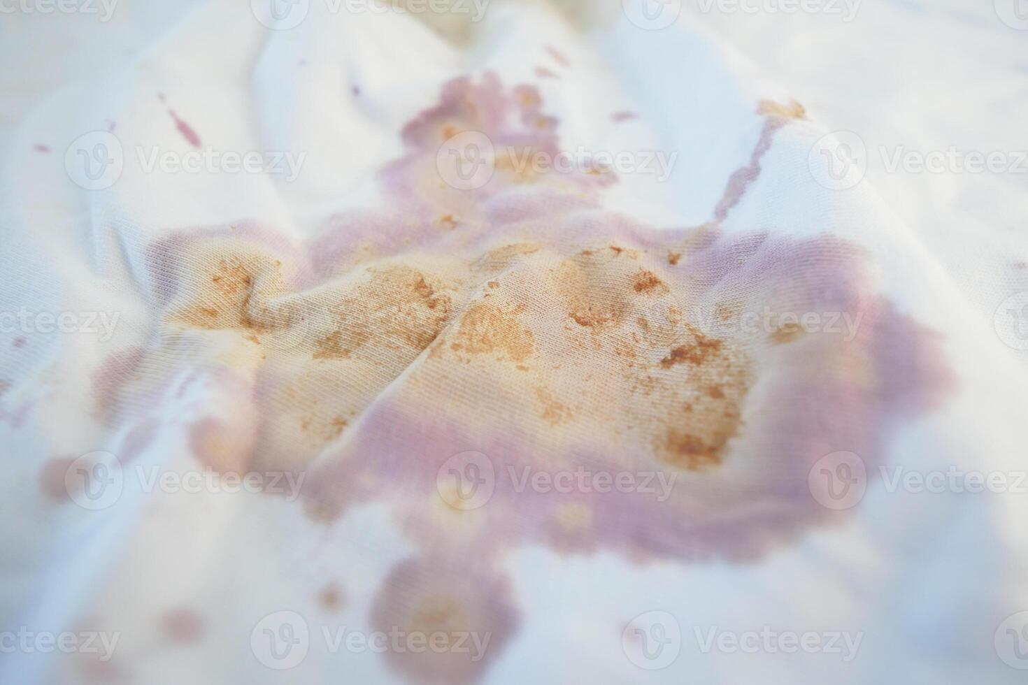 Stained fabric with purple and brown splotches on a light surface photo