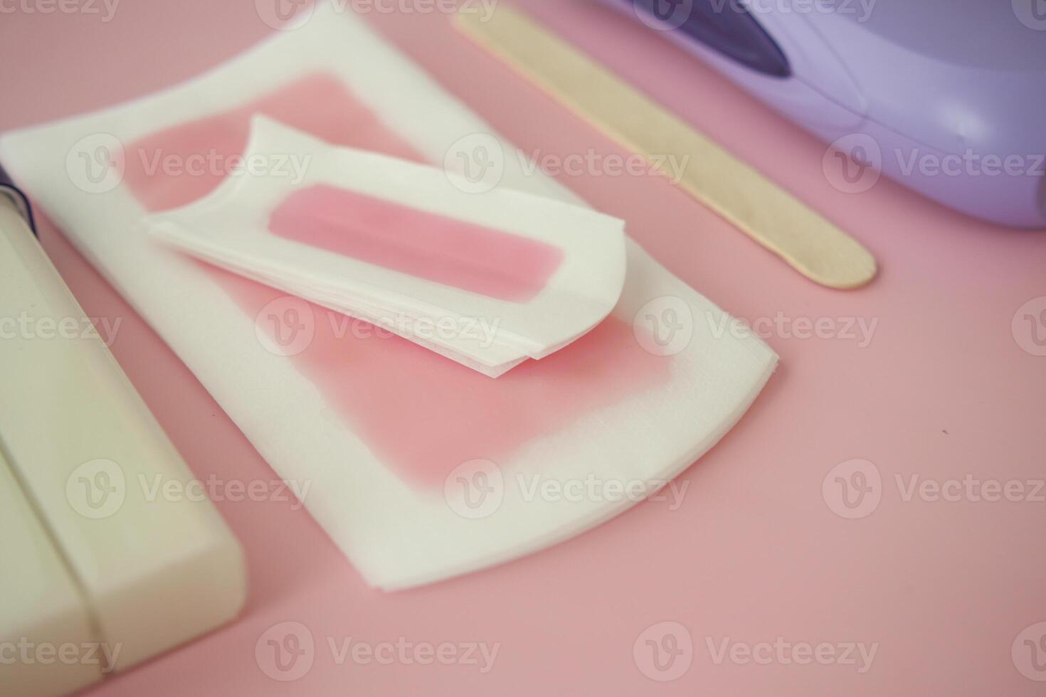 Waxing supplies arranged on a pink surface for personal care photo