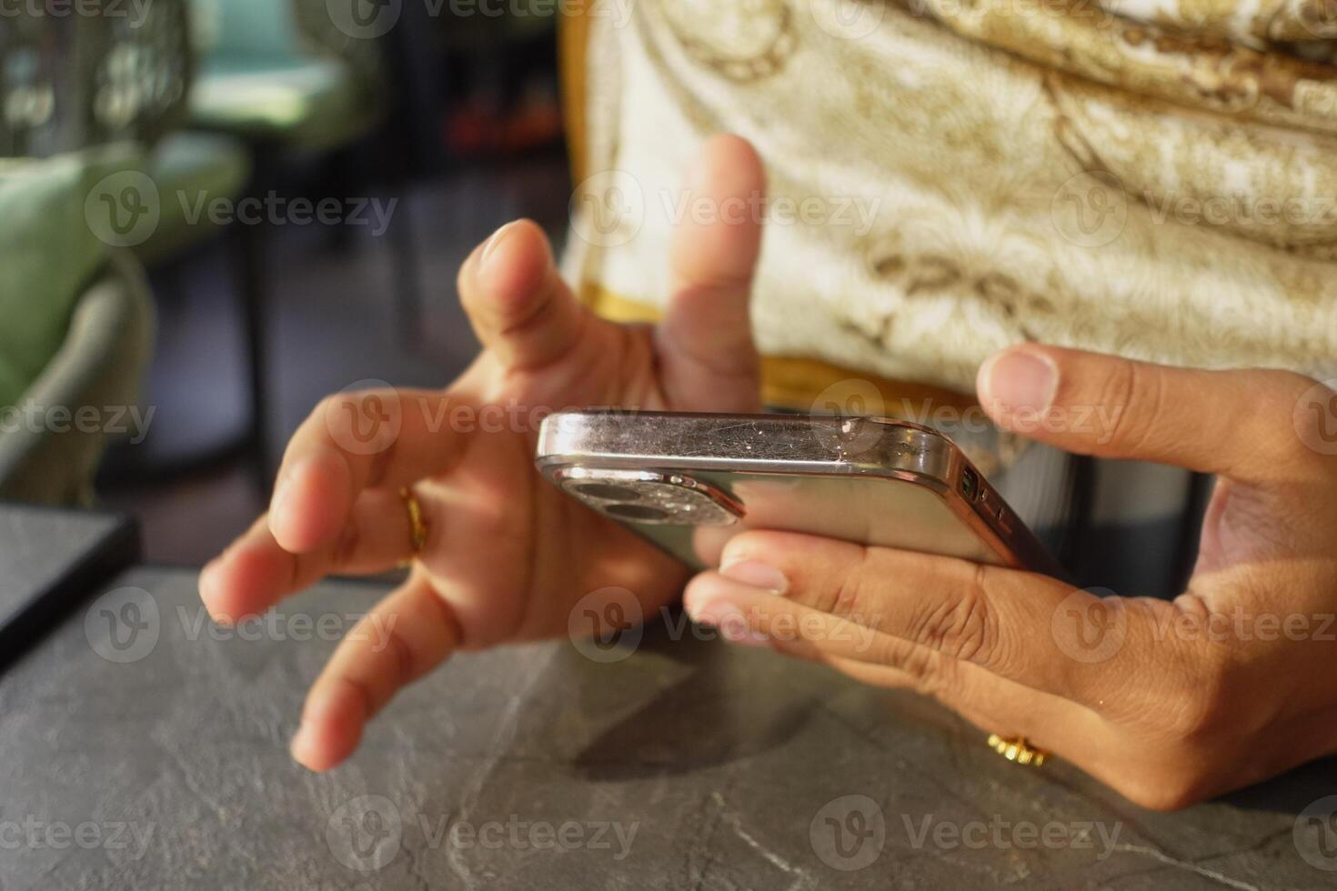 Engaging with a smartphone while seated in a cozy cafe setting photo