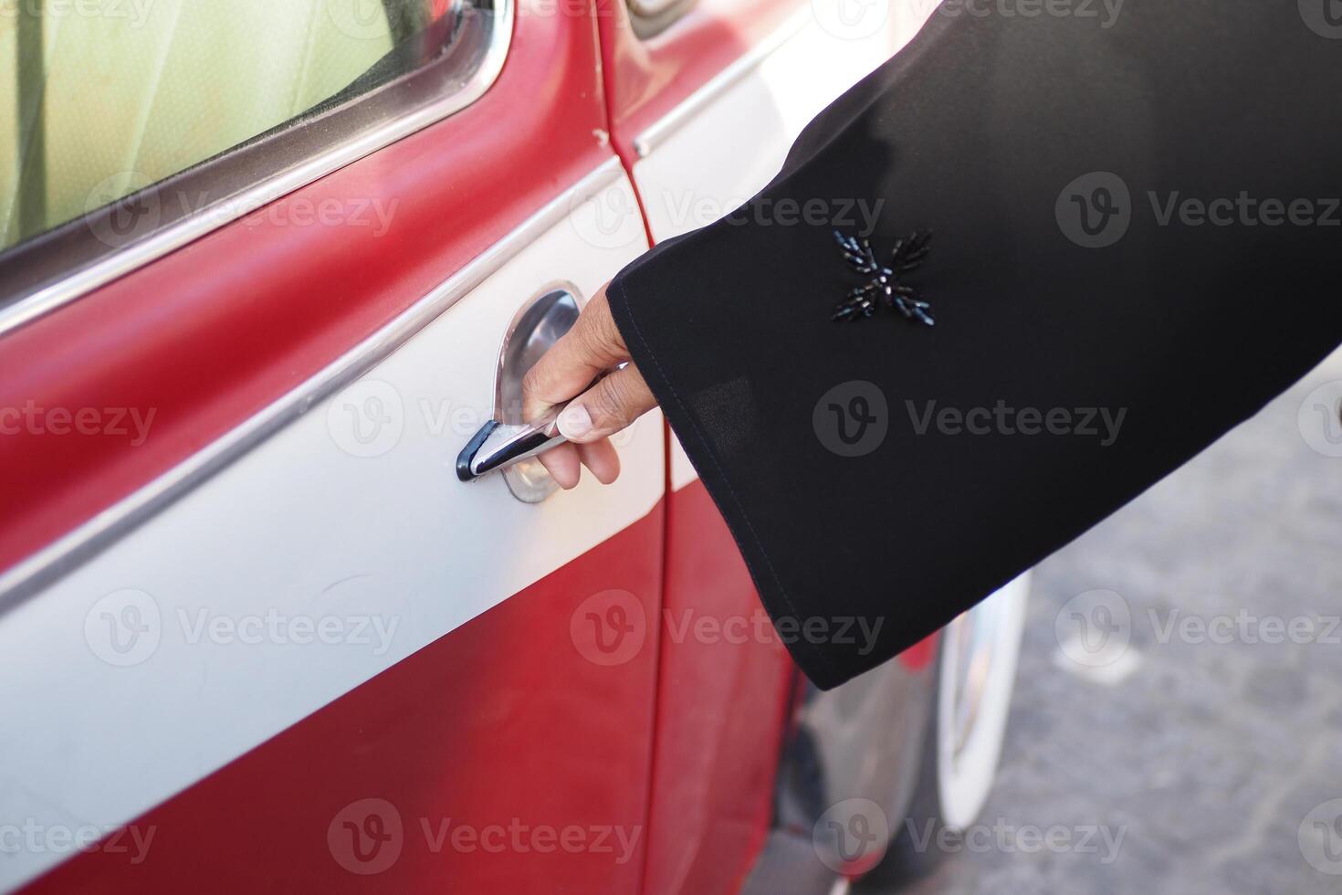 Hand reaching for car door on a vintage red vehicle at midday photo