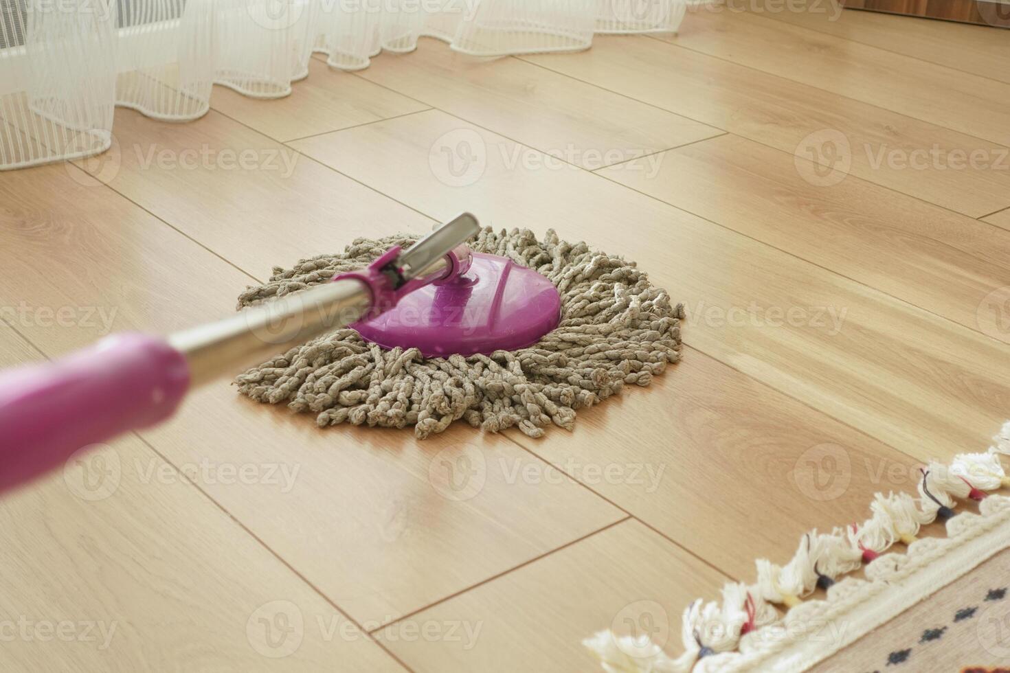 Cleaning a wooden floor with a mop in a bright room photo