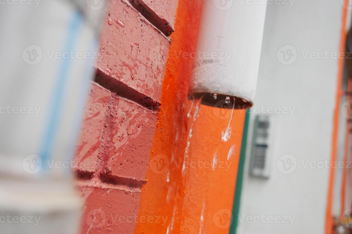 Water dripping from a rain gutter on a colorful wall photo