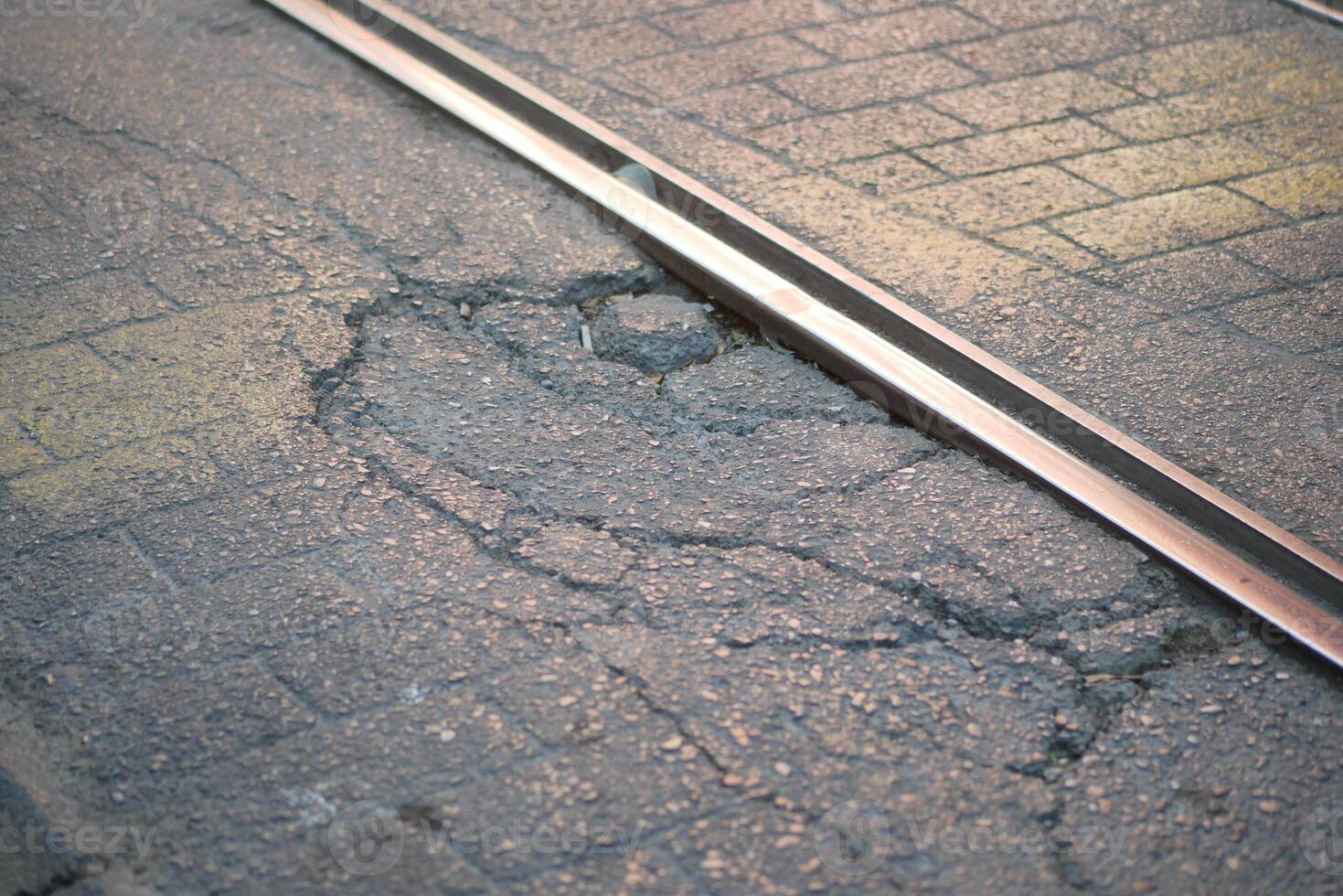 Pavement cracks beside railway tracks in an urban setting photo