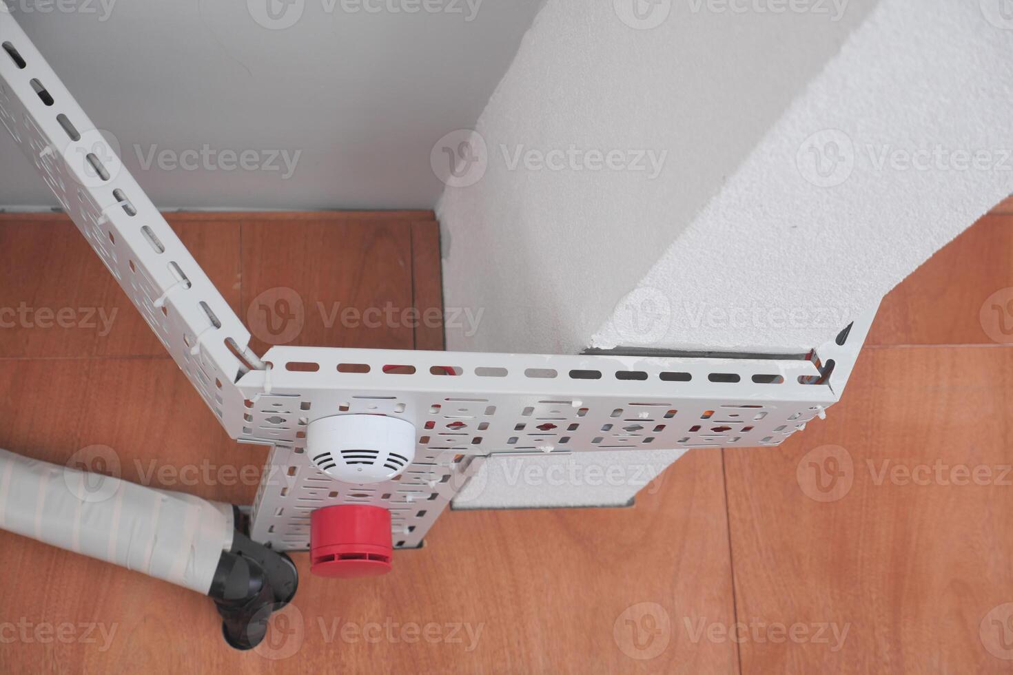 Metal brackets and a fire alarm are securely mounted in a building photo