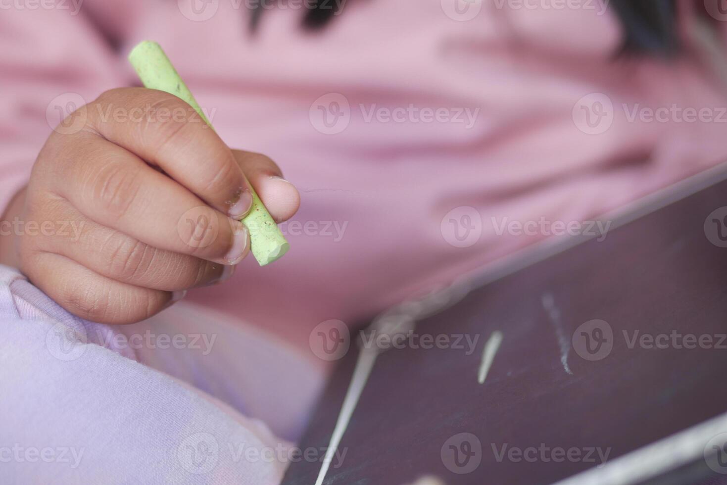 Child drawing with chalk on a small blackboard at home photo