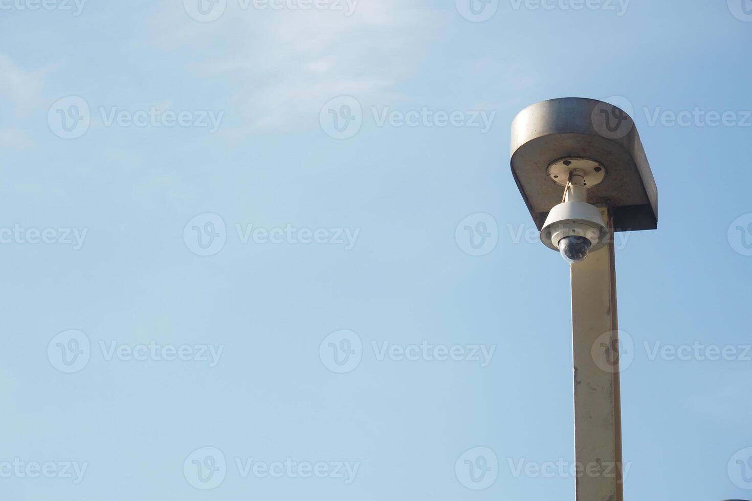 Security camera mounted on pole under clear blue sky photo