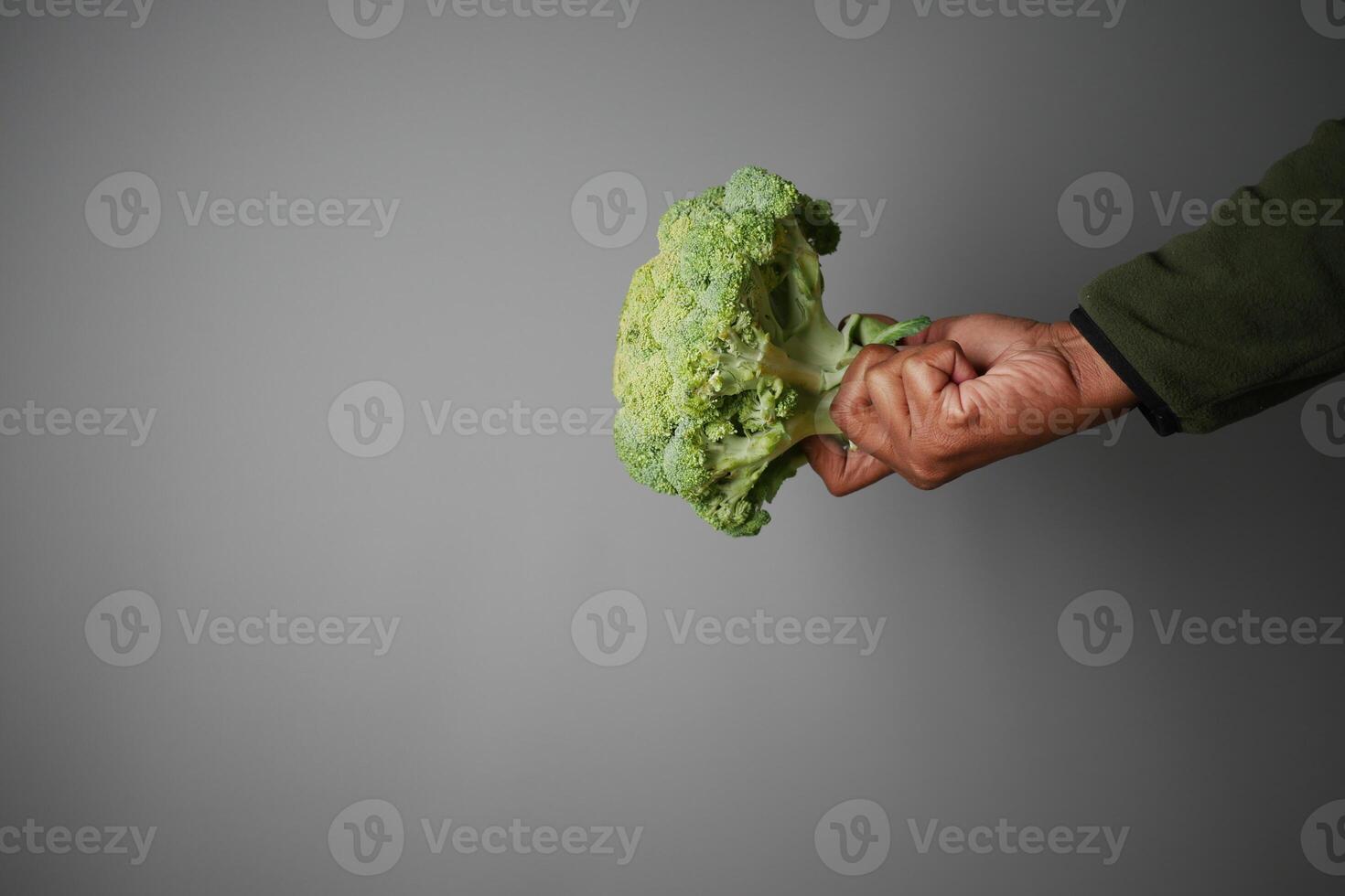 Broccoli held confidently against a gray background photo