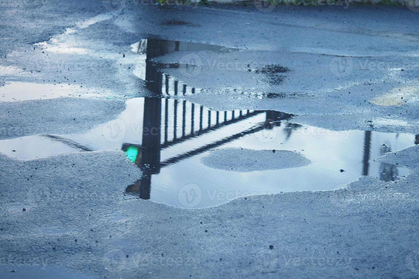 Puddle reflecting a fence and light after rain in a parking lot photo