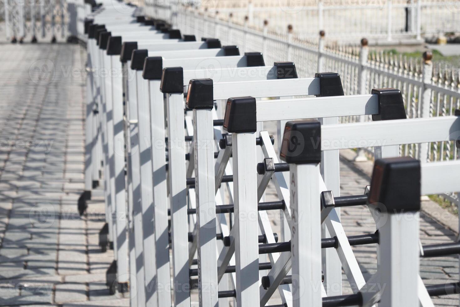 White barricades line pathway in a public area on a sunny day photo