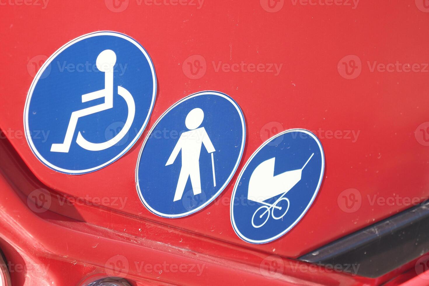 Various accessibility symbols displayed on a red vehicle's surface photo