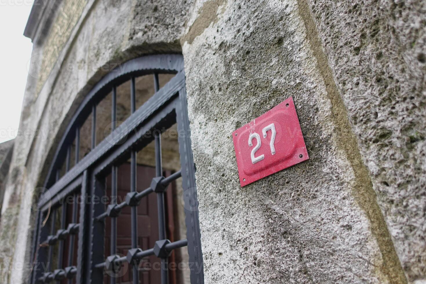 Historic stone wall with number 27 and iron gate details in focus photo