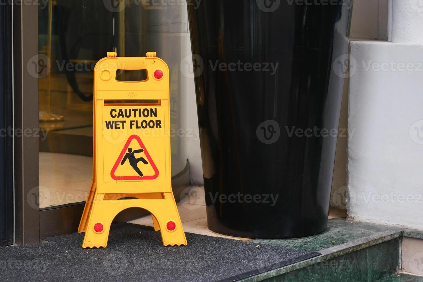 Caution sign warns about wet floor near entrance of a building photo