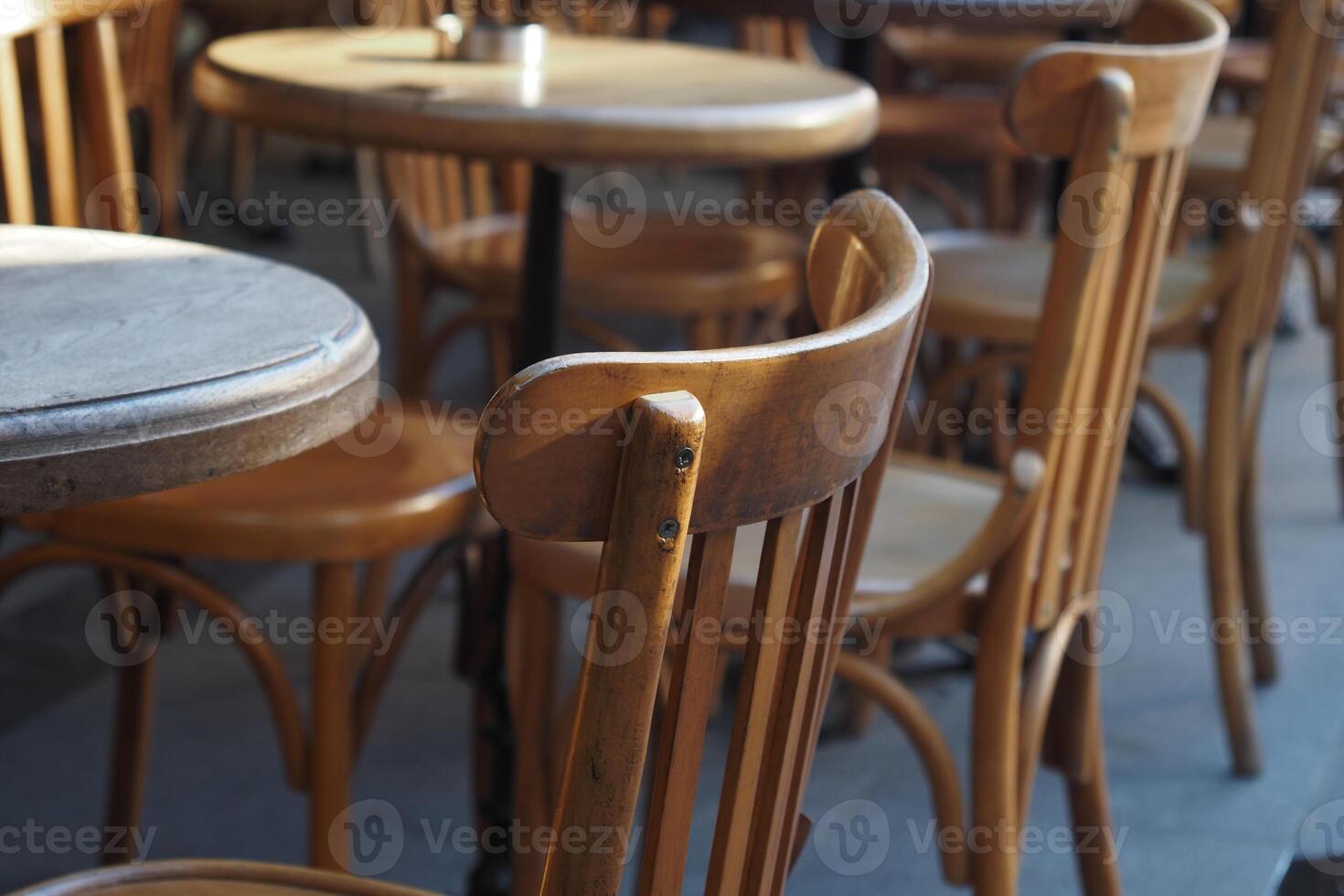 Rustic wooden chairs and tables in a lively cafe setting photo