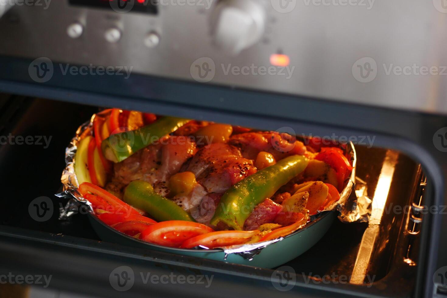 Delicious meal baking with fresh vegetables and meat in oven photo