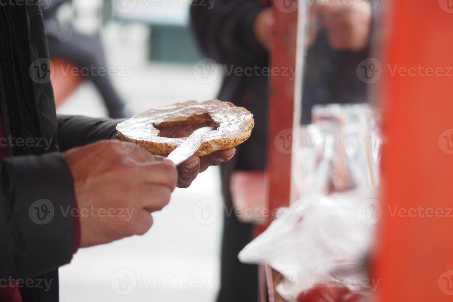 Person preparing a snack with a spread at a street cart photo