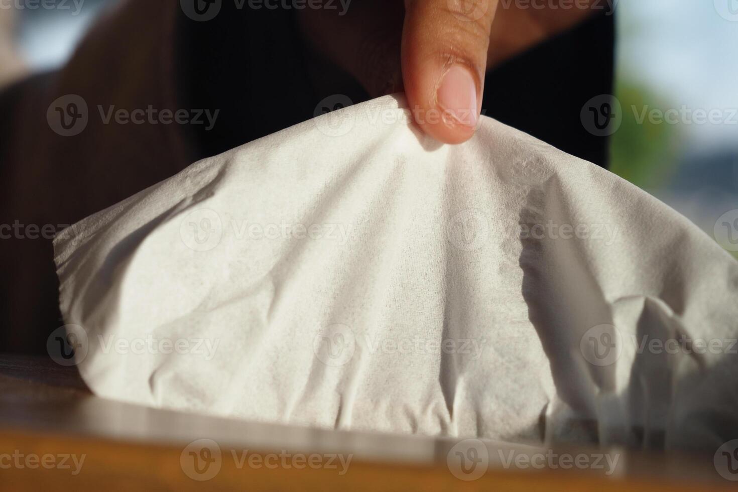 Hand holding a wrapped food item on a wooden table in a cafe photo