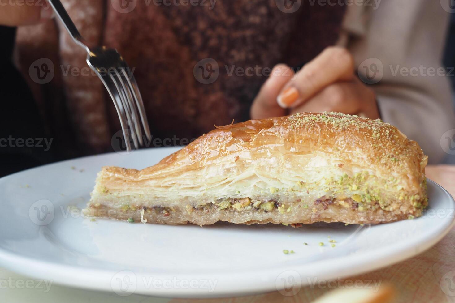 Delicious baklava dessert served on a plate with fork and hand photo