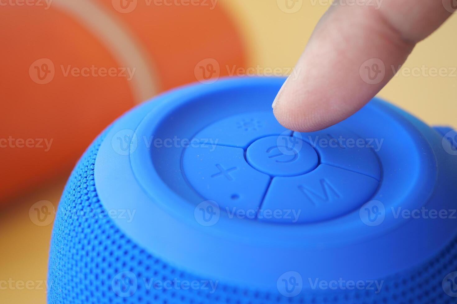 Close up of blue speaker control with finger pressing button photo