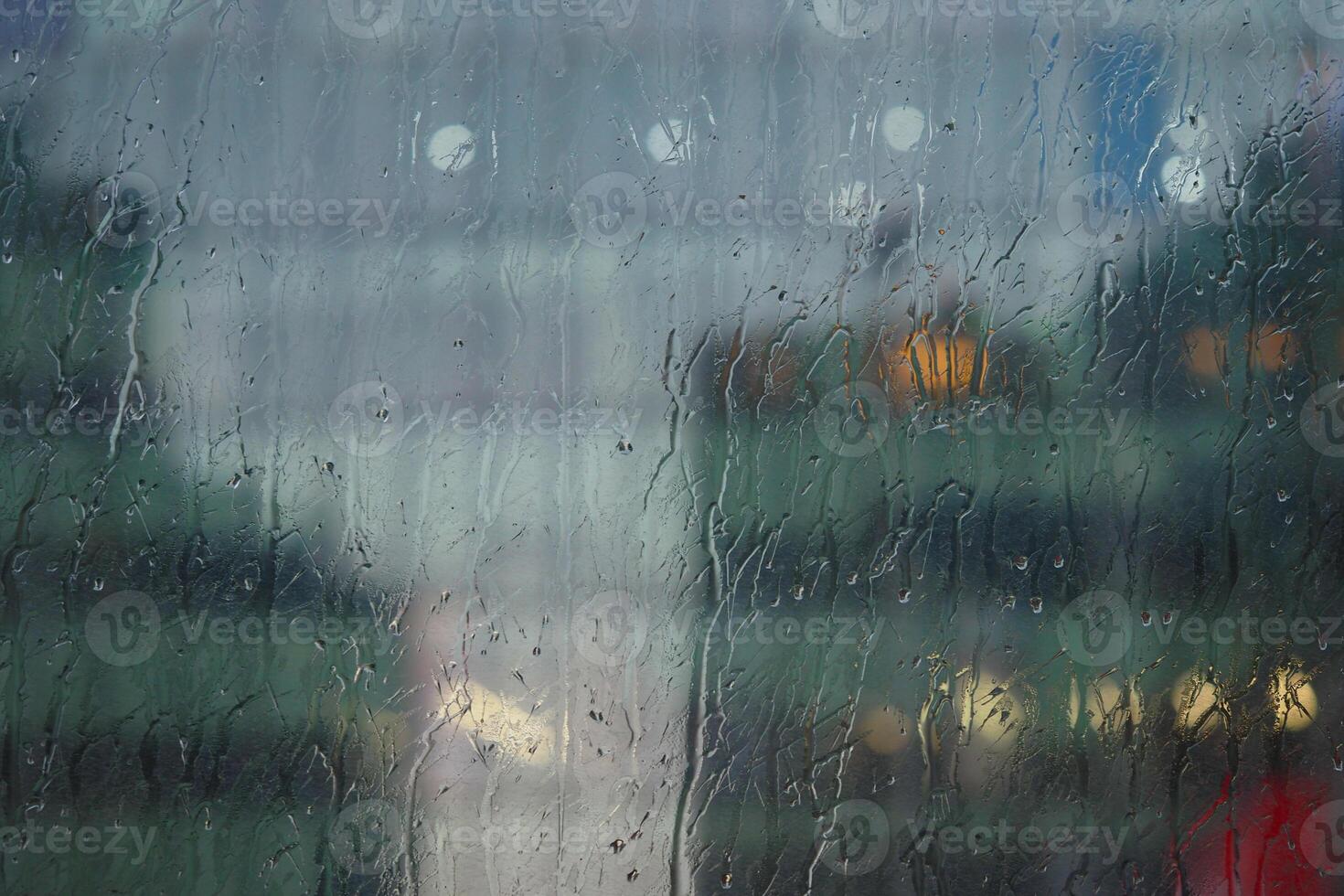 Rainy day view through a window with blurred city lights photo