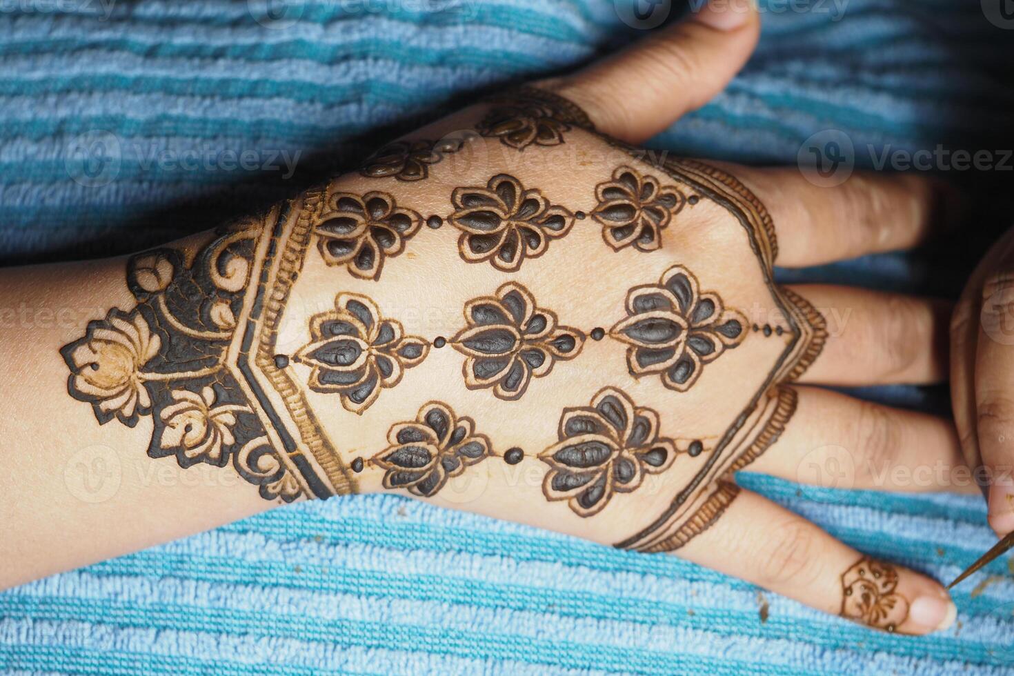 Floral henna design on hand with blue fabric backdrop photo