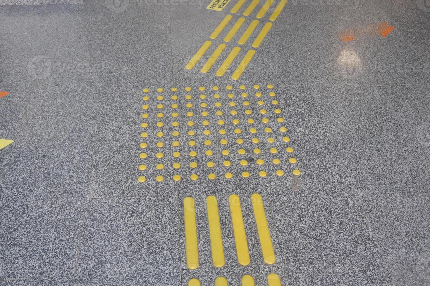 Yellow tactile guide lines on a public space floor in an urban area photo