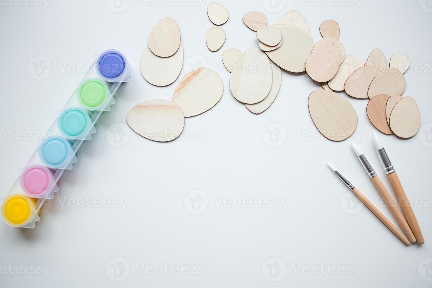 Wooden Easter egg shapes with paint and brushes with copy space for creative crafting photo