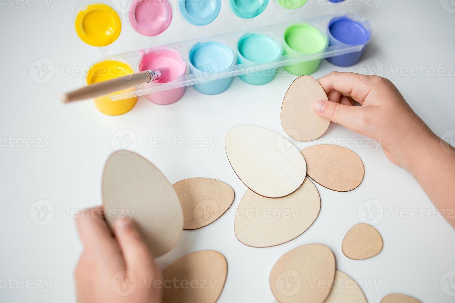 Child painting wooden Easter eggs with colorful paints photo