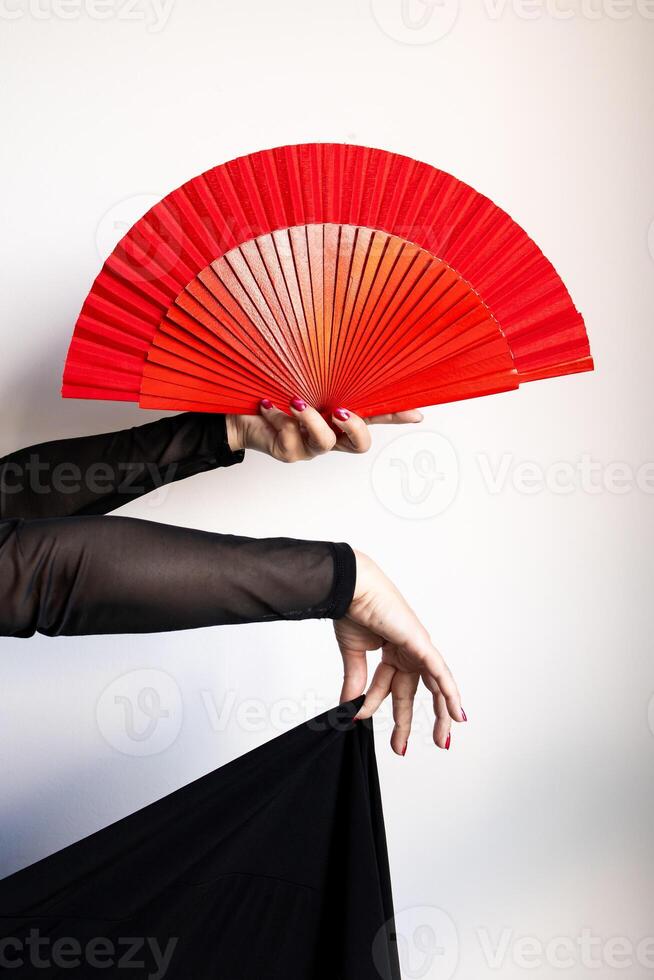 Elegant display of red asian fan in female hands with black dress and sheer sleeves photo